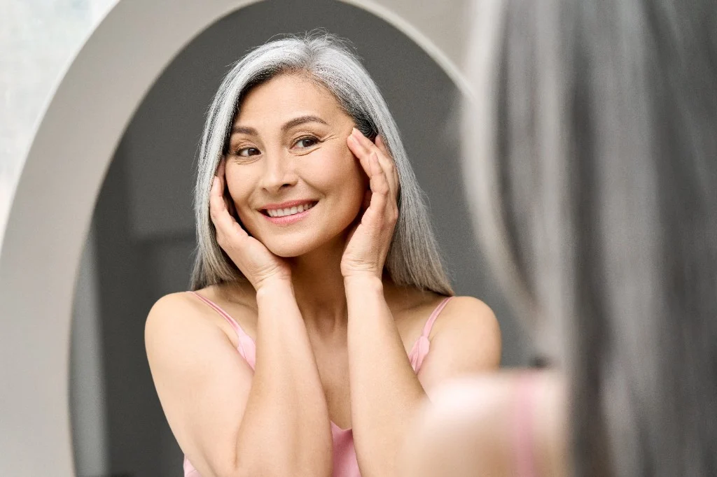Patient admiring smoother skin in the mirror after wrinkle reduction treatment